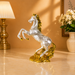 A metallic silver horse figurine with a gold crown and gold accents on its mane, tail, and base, displayed on a polished beige marble surface in a warm, decorated room.