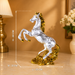 A metallic silver horse figurine with a gold mane, tail, and base, shown on a tabletop with overlaid dimension lines indicating height, width, and length.