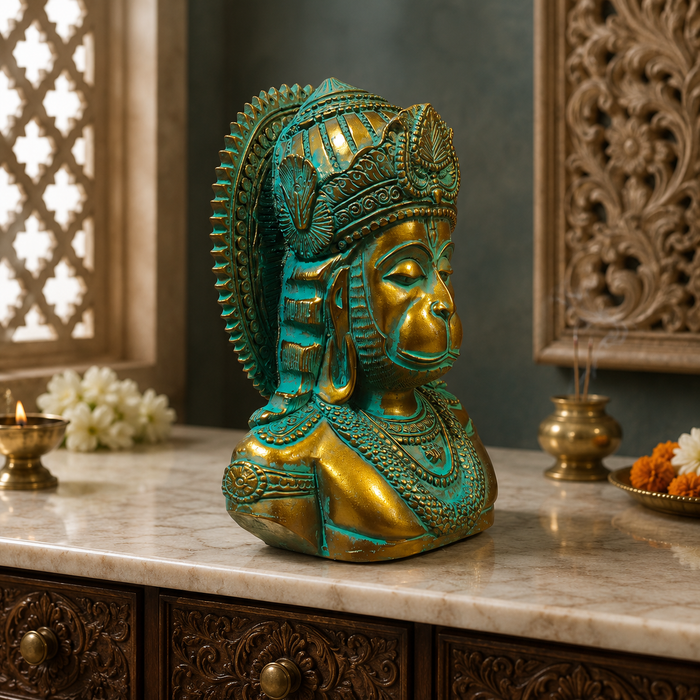 A decorative Lord Hanuman bust statue with a green patina finish, displayed on a marble countertop in a styled home decor setting.