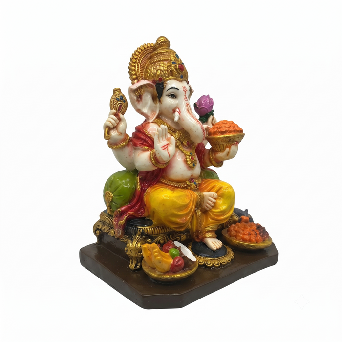 A colorful statue of Lord Ganesha seated on a dark brown base, with a white elephant head, gold ornaments, and yellow pants, holding a bow and a bowl of sweets against a plain white background.