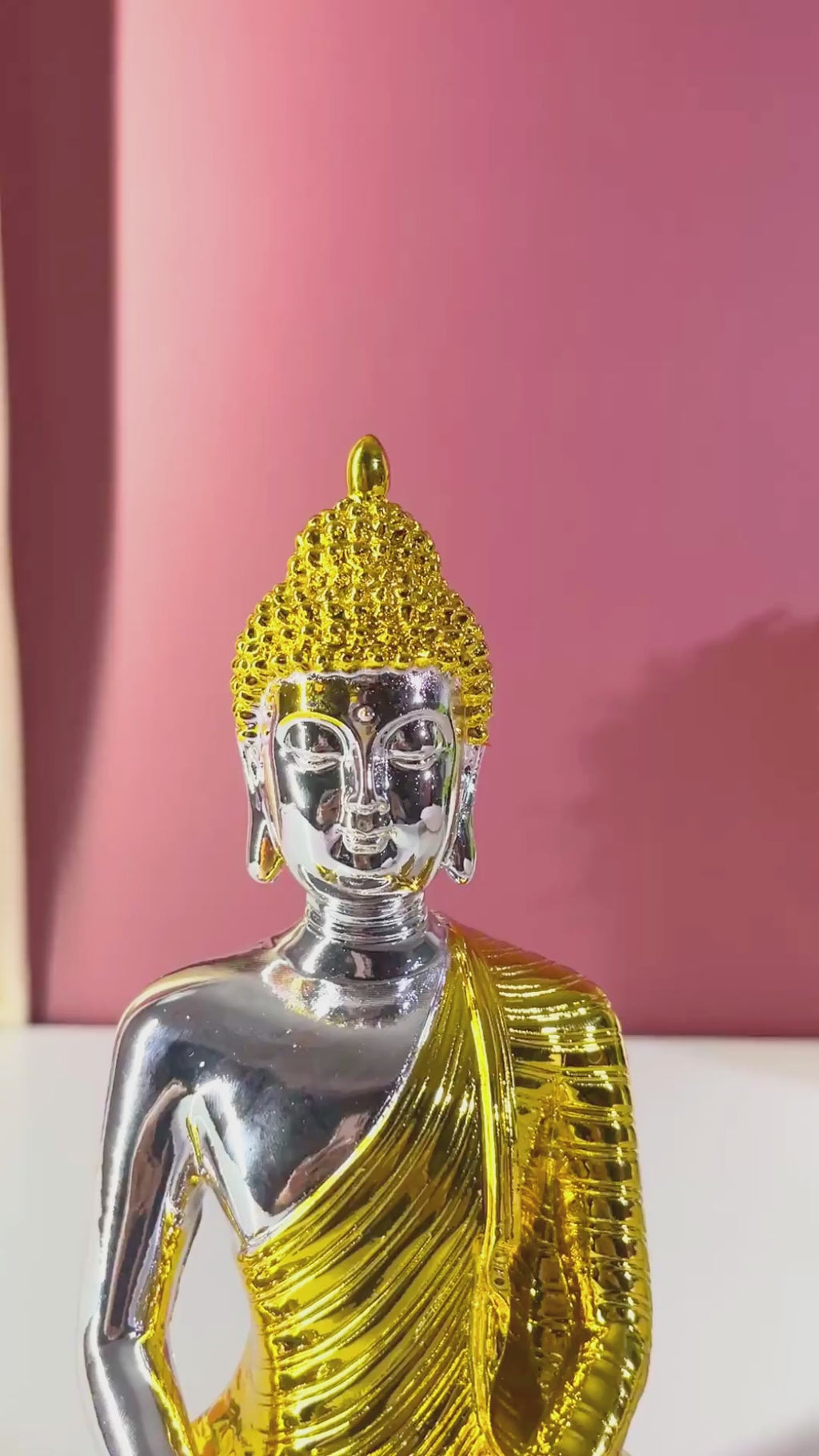 A metallic gold Buddha statue in a seated meditation pose, 