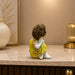 A side profile view of the Yellow Little Buddha Figurine revealing its graceful silhouette.